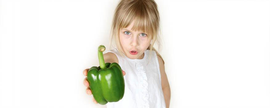 Kleines Mädchen mit grüner Paprika